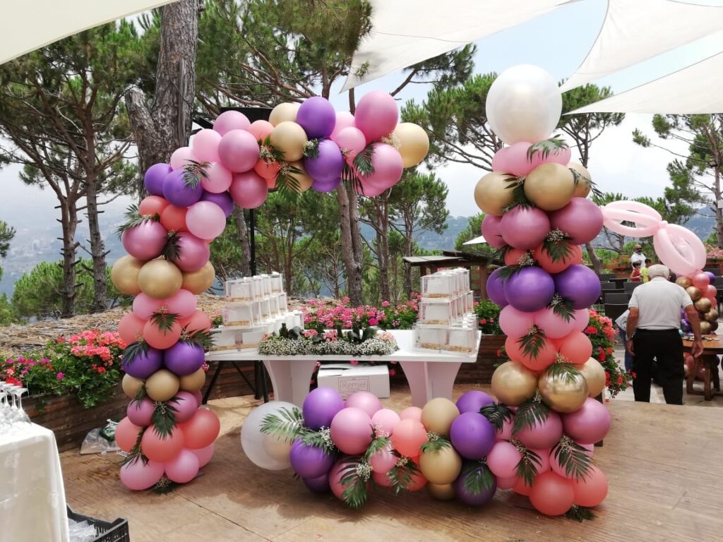 a balloon arch with a table and flowers