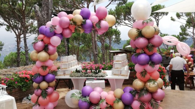 a balloon arch with a table and flowers