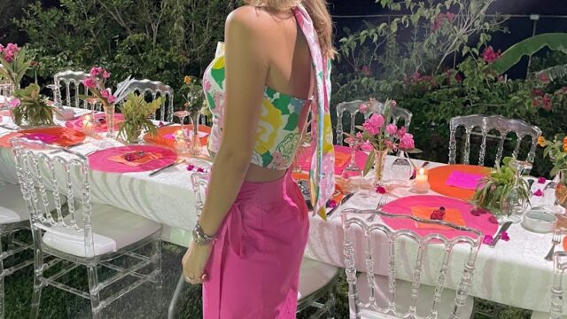 a woman standing in front of a table with chairs and flowers