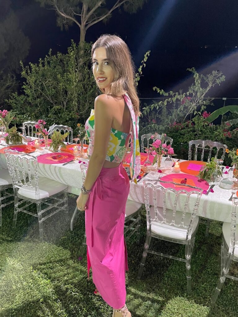 a woman standing in front of a table with chairs and flowers