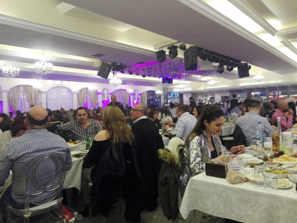 a group of people sitting at tables in a room with purple lights