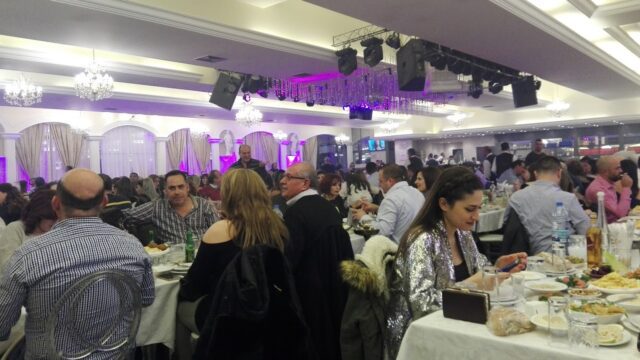 a group of people sitting at tables in a room with purple lights