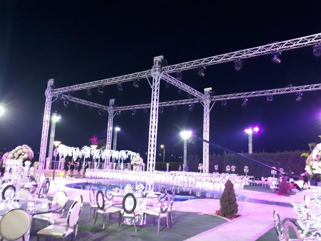 a white structure with chairs and a pool with lights at night