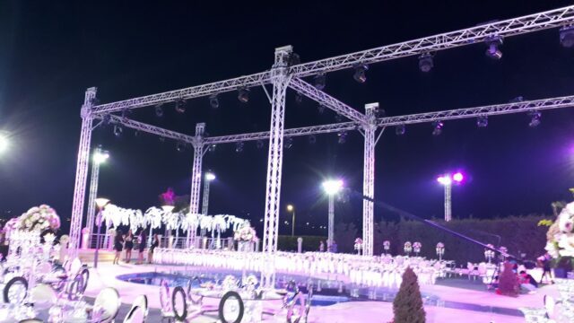 a white structure with chairs and a pool with lights at night