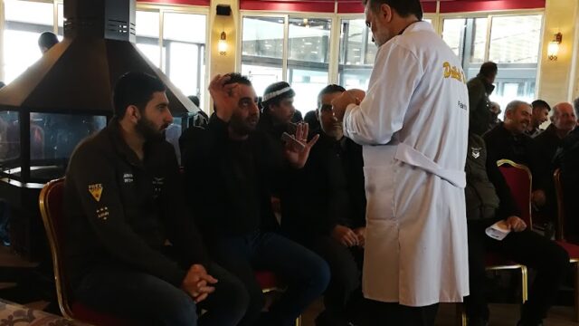 a man in a white coat speaking to a group of people