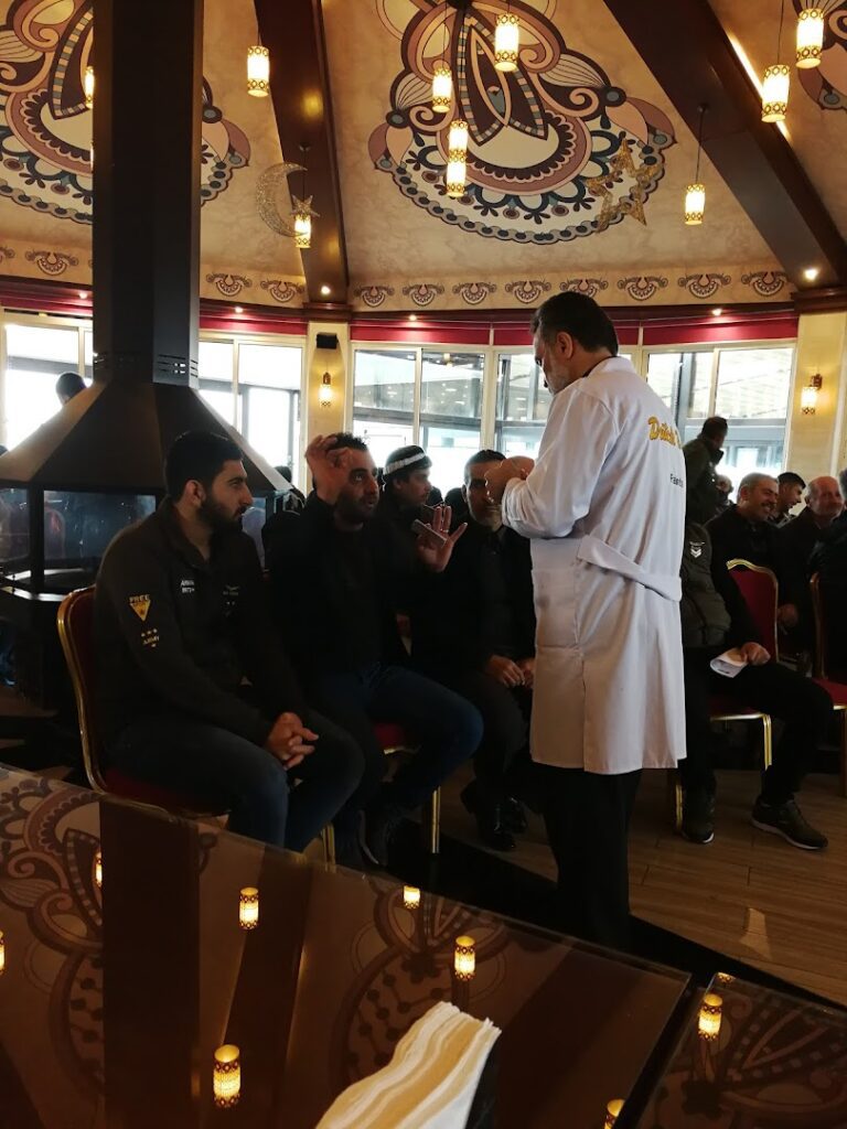 a man in a white coat speaking to a group of people