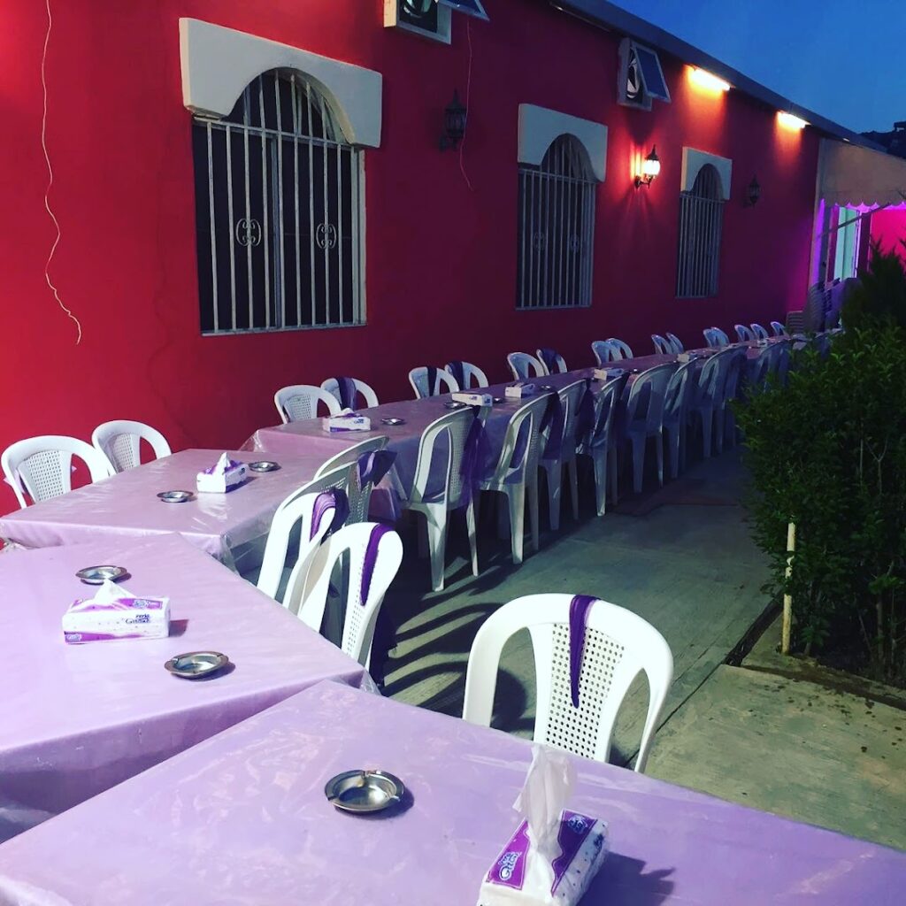 a row of tables with purple tablecloths and white plastic chairs