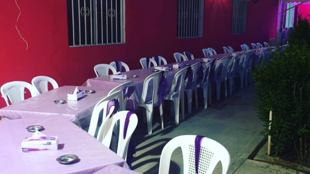 a row of tables with purple tablecloths and white plastic chairs