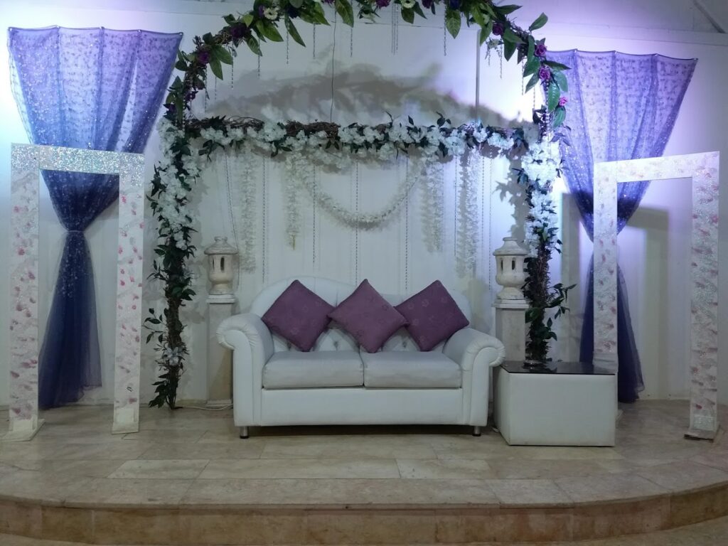 a white couch with purple pillows and a white arch with purple curtains