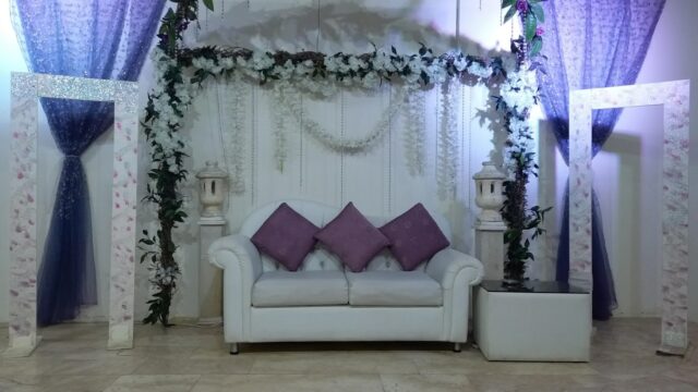 a white couch with purple pillows and a white arch with purple curtains