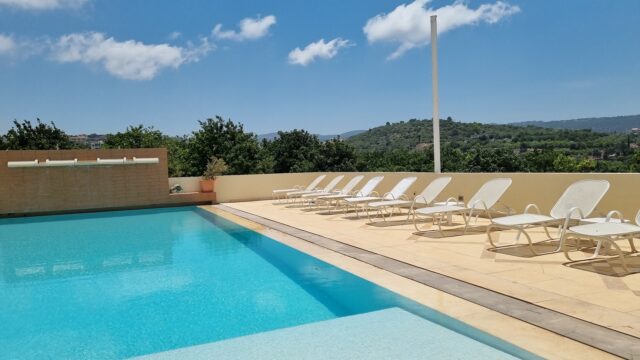 a pool with chairs and trees in the background