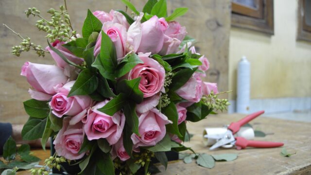 a bouquet of pink roses and scissors on a wood surface