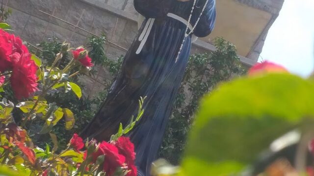 a statue of a nun holding a cross in a garden