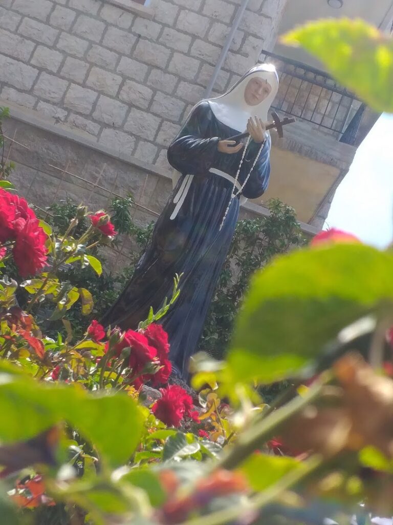 a statue of a nun holding a cross in a garden