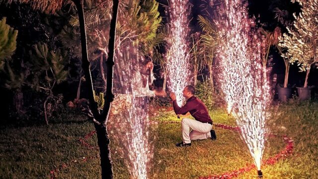 a man kneeling in a grass field with fireworks