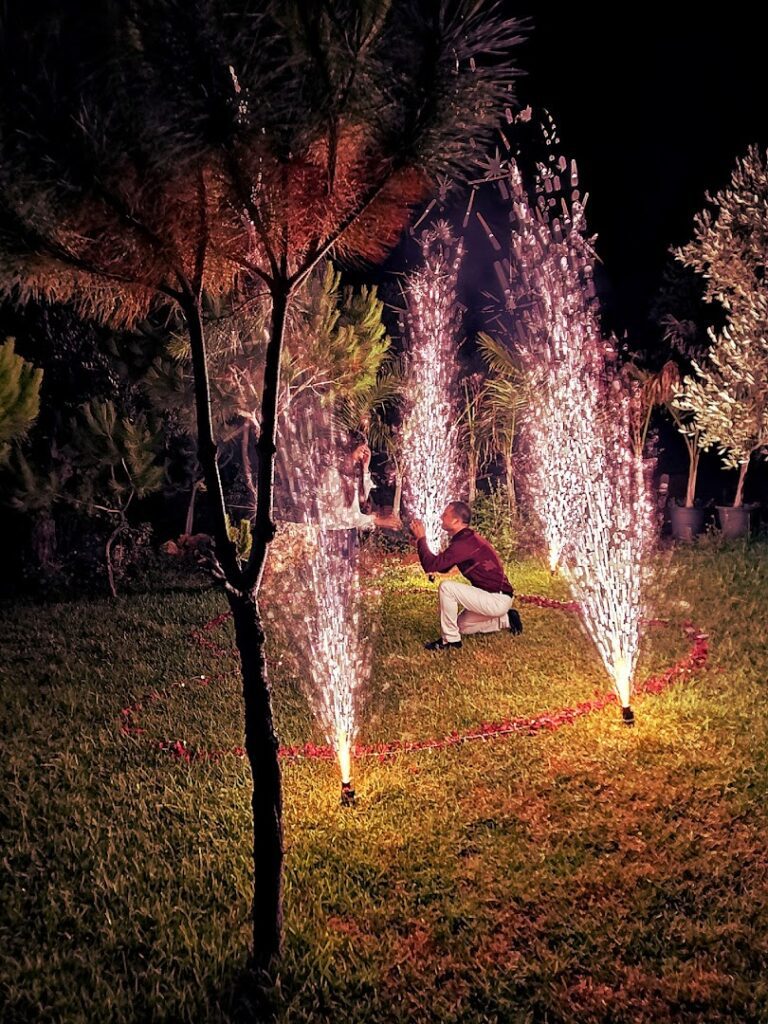 a man kneeling in a grass field with fireworks