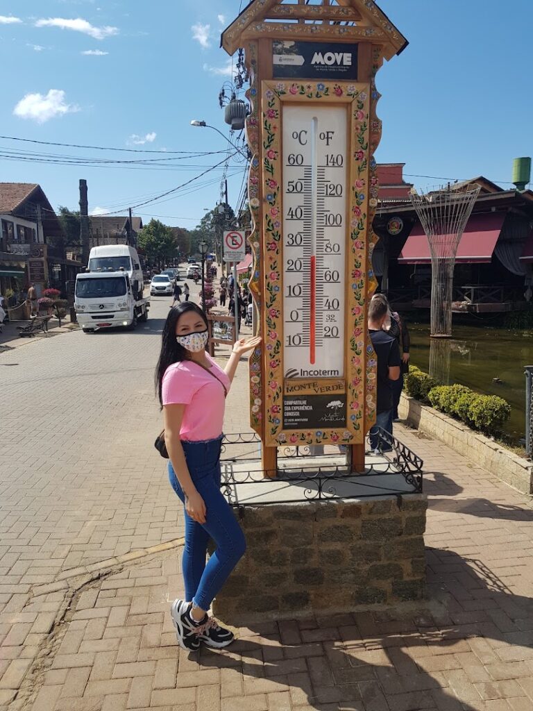 a woman wearing a face mask standing next to a thermometer
