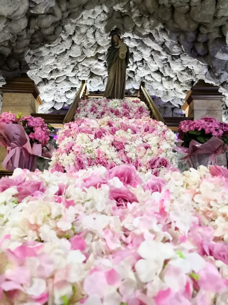 a statue of a woman with a statue on a staircase surrounded by flowers