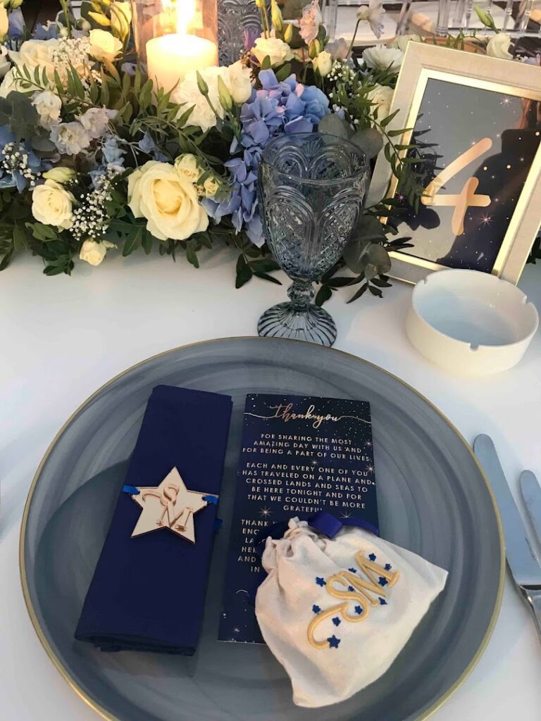 a plate with a napkin and a bag on it next to a bouquet of flowers