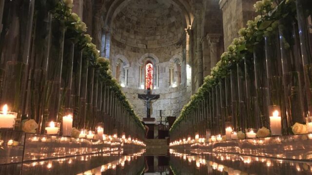 a long row of glass vases with flowers and candles in them