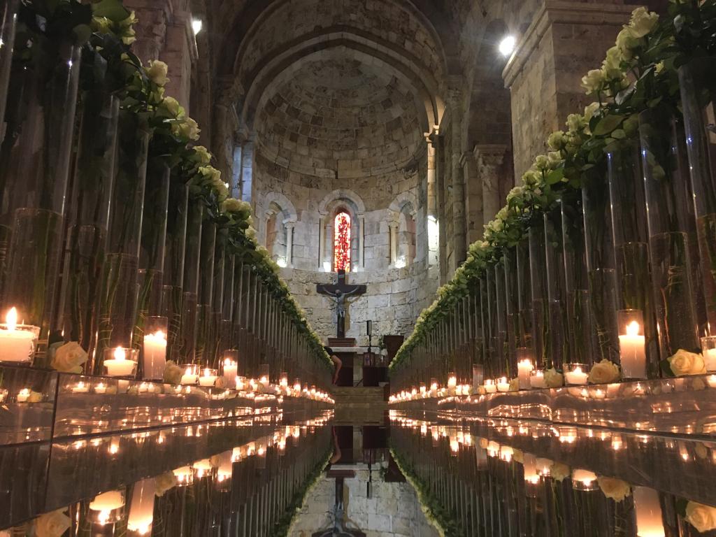 a long row of glass vases with flowers and candles in them