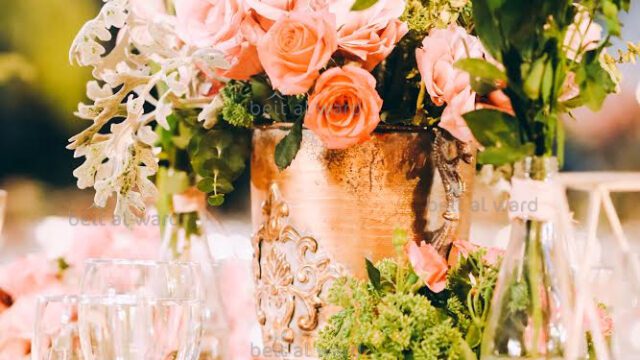 a vase with flowers and glasses on a table