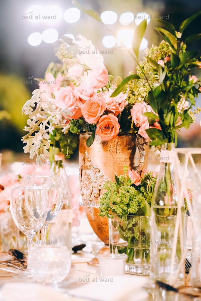 a vase with flowers and glasses on a table