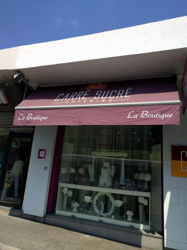 A store front with a purple awning belonging to "Carré Sucré Main Office & Central Kitchen".