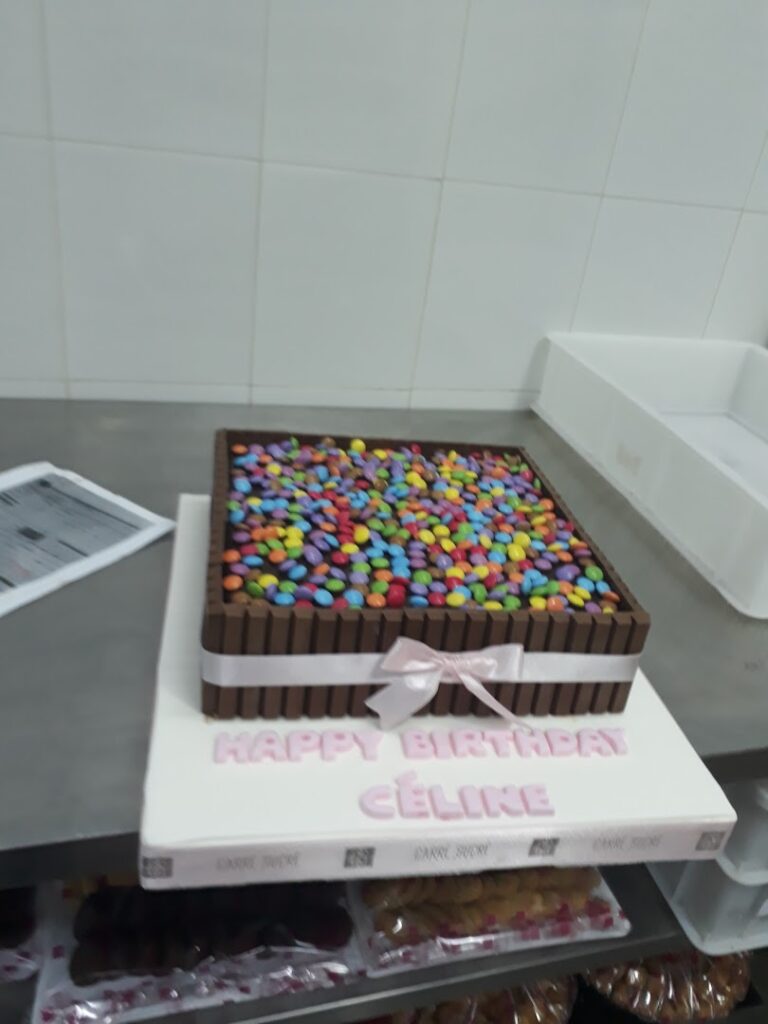 A Carré Sucré "Main Office & Central Kitchen" cake with candy on it.