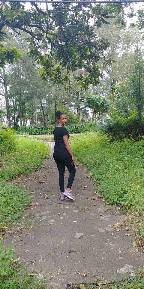 A woman standing on a path in a park near the "Carré Sucré Main Office & Central Kitchen."