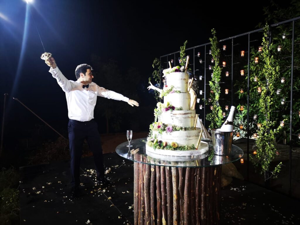 A man standing next to a cake, Catering by Muscat.
