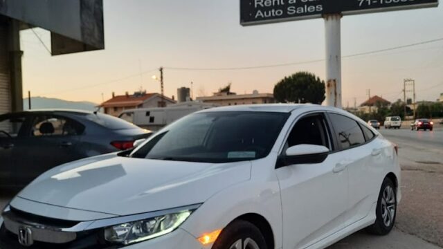 a white car parked in front of a sign