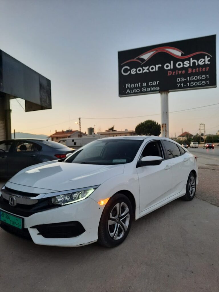 a white car parked in front of a sign