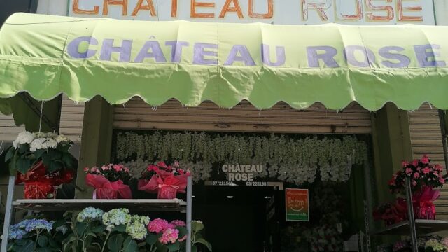 a store front with flowers and a sign