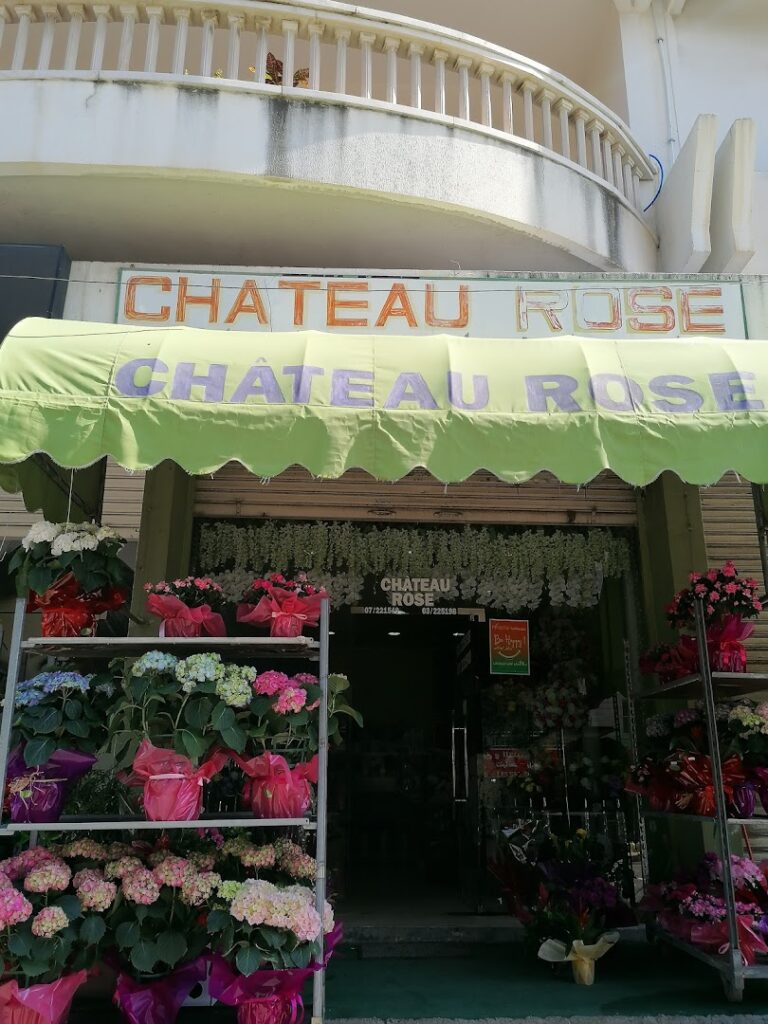 a store front with flowers and a sign