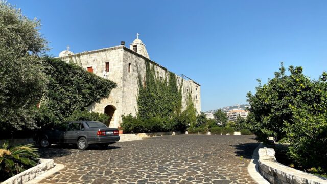 a stone building with trees and a car parked in front of it