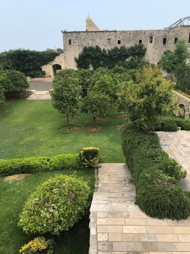 a stone building with a garden and bushes