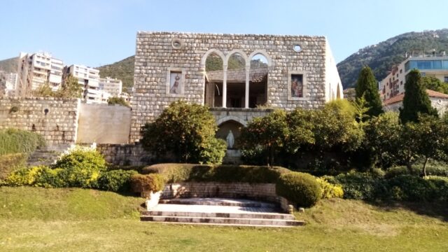 a stone building with a lawn and a fountain