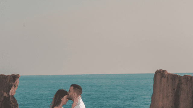 a man and woman kissing on a beach