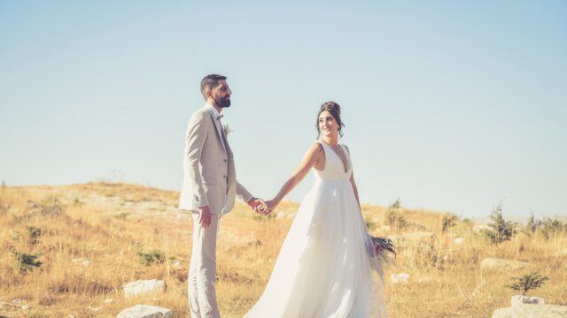 a man and woman holding hands and standing in a field