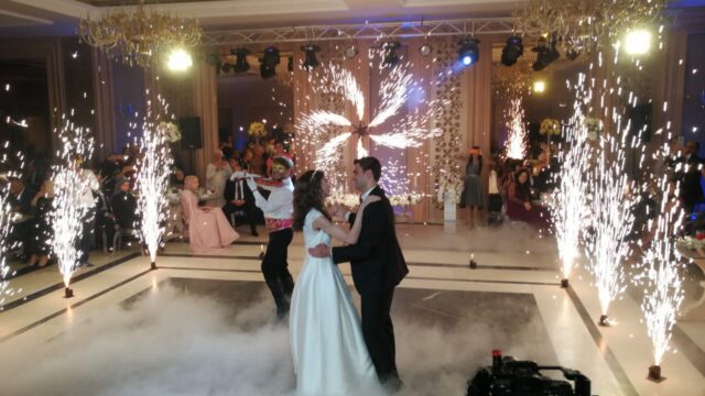 a couple dancing in a room with fireworks