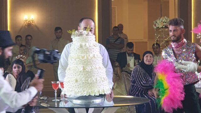 a man standing next to a cake