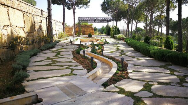 a stone path with a stone wall and trees