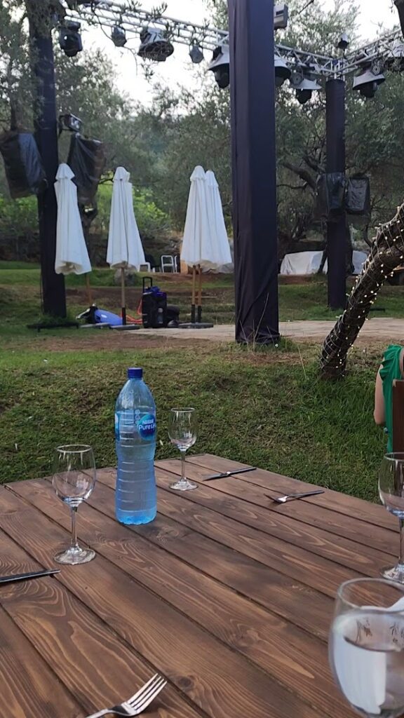 a table with a bottle of water and wine glasses on it