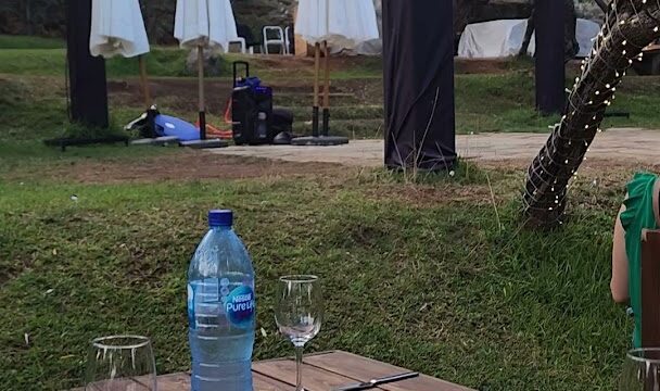 a table with a bottle of water and wine glasses on it