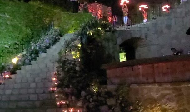 a group of people standing on a stone staircase with candles on them