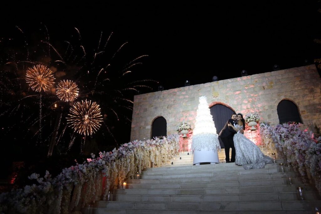 a couple standing on stairs with fireworks in the background