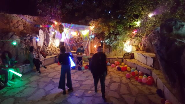 a group of people walking in a courtyard with colorful lights