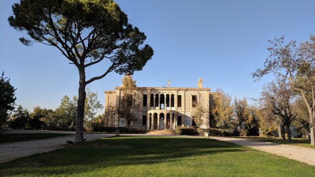 a large stone building with a lawn and trees