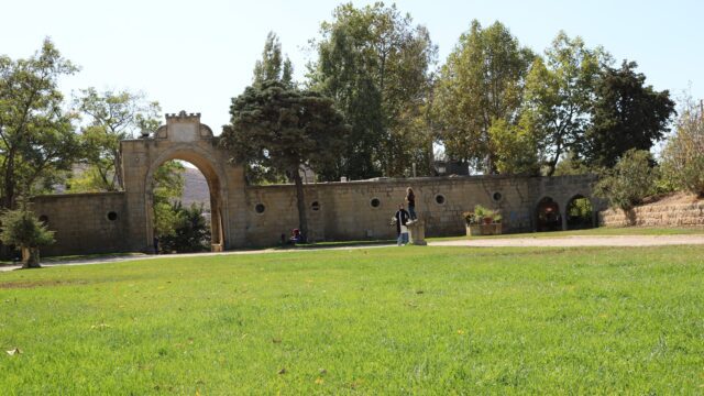 a stone wall with a stone archway and trees